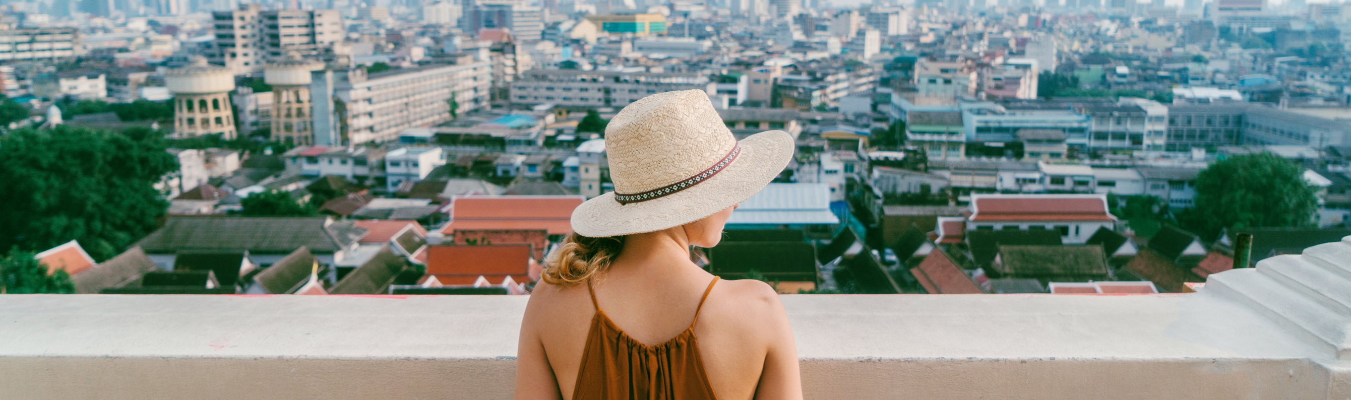 Frau mit Hut überblickt eine dichte Stadt.