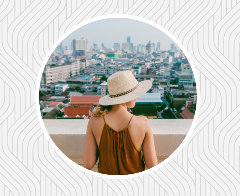 Woman in hat overlooking a dense city.