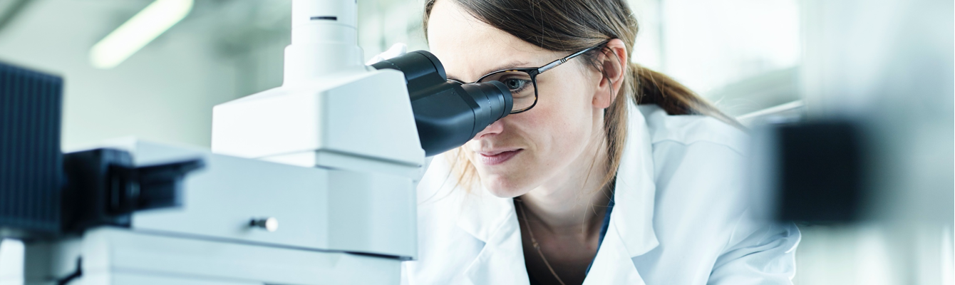 Woman scientist looking through microscope - J&J Consumer Health
