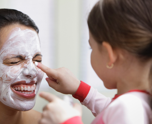 Mother and daughter playing with moisturizer on face