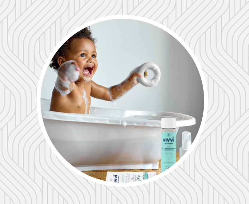 Smiling baby in small tub with toys and bath products 